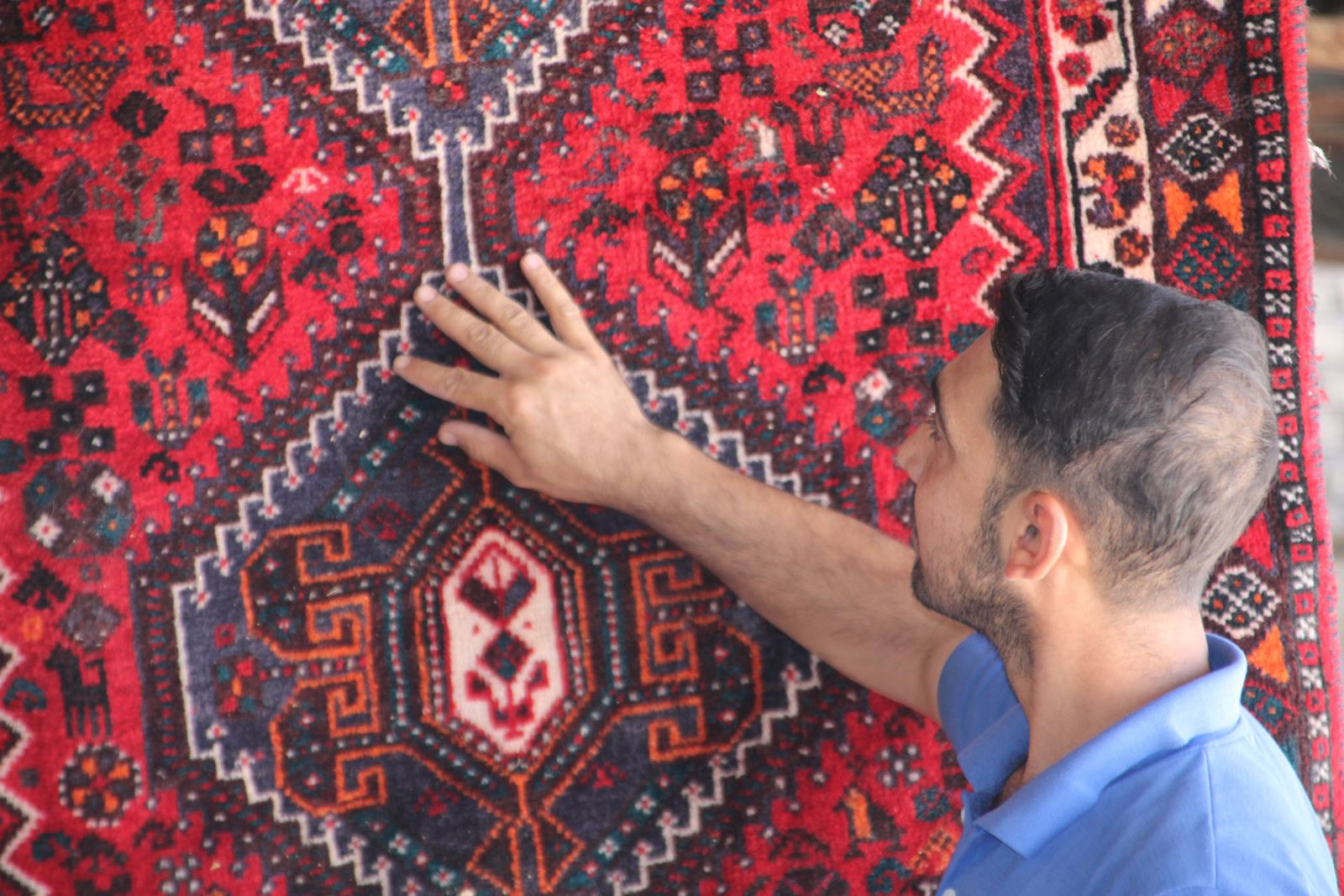 کارشناس در حال بررسی کیفیت پرداخت و یکنواختی پرزهای فرش دستباف